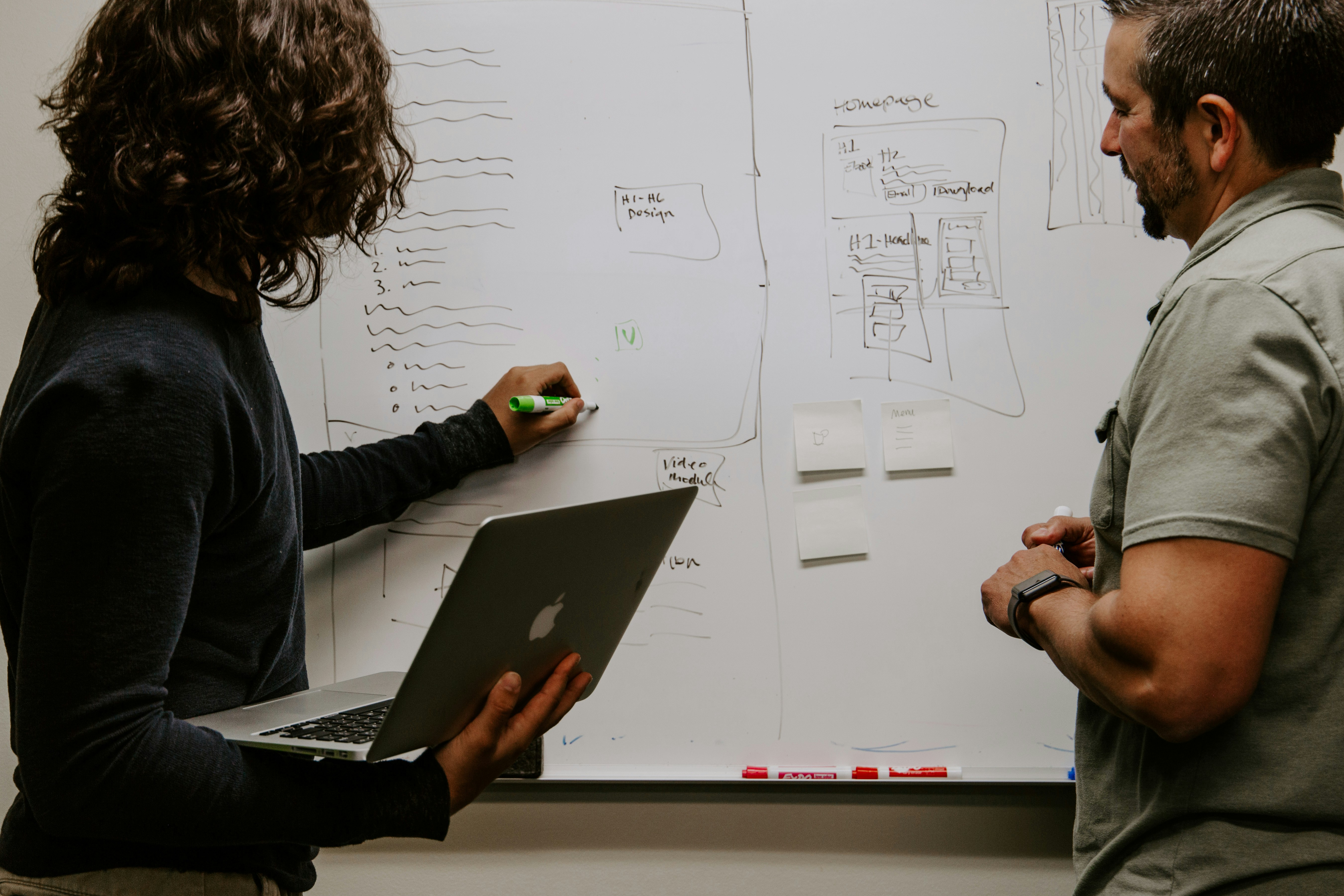Team members collaborating on whiteboard with technical sketches and design wireframes