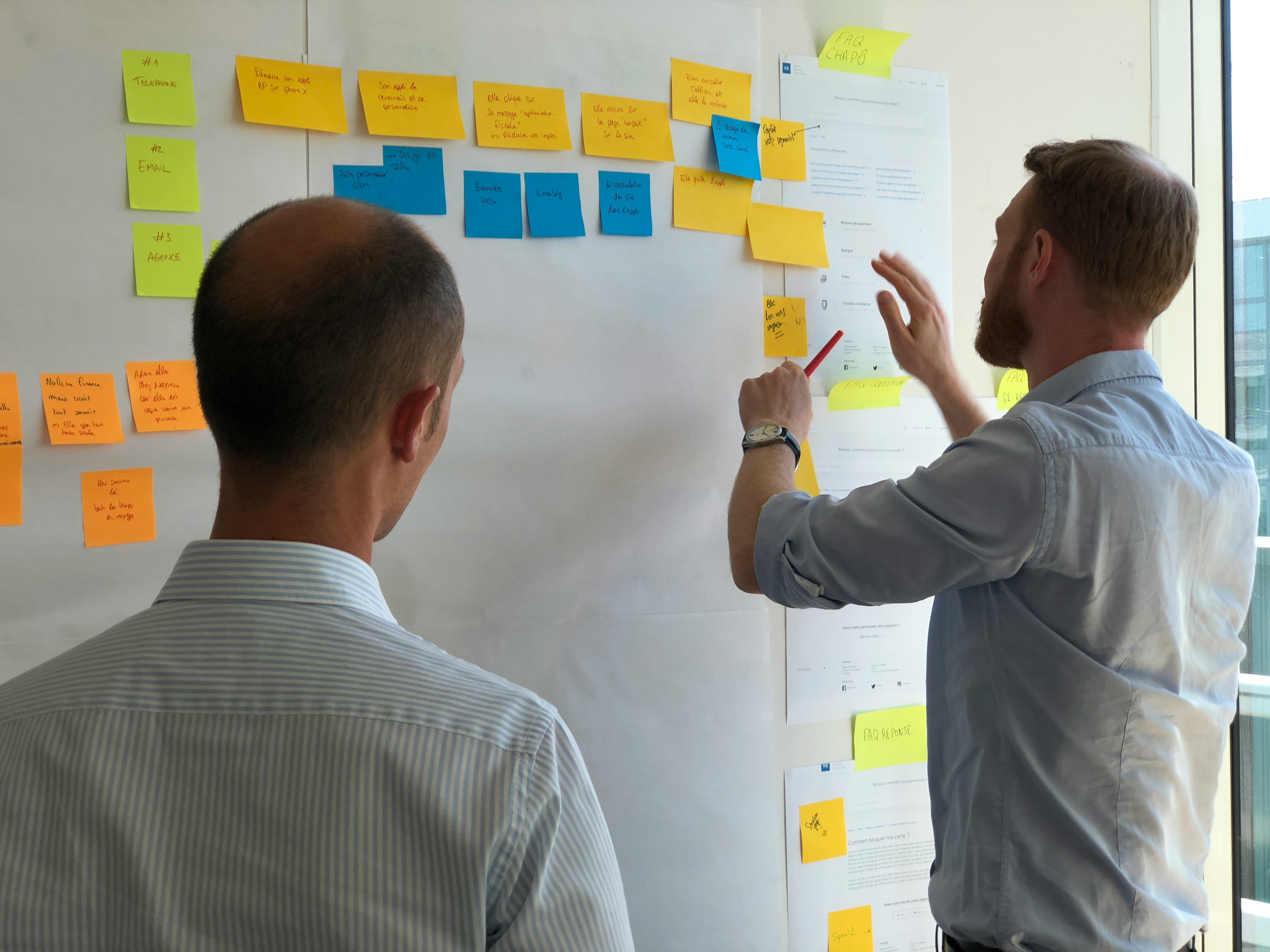 Professionals collaborating with colorful sticky notes on whiteboard demonstrating senior leadership